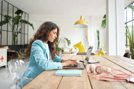 Close up of beautiful young business woman typing on laptop keyboard. Female office worker in formal suit works concentrated on work in modern office in slow motion.の写真素材