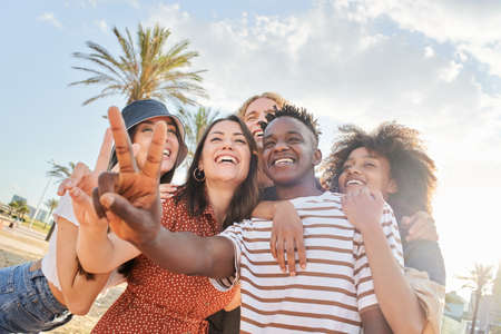 A group of young people take a selfie taking the victory sign. Concept of celebrating success, students, friendship, happiness.の写真素材
