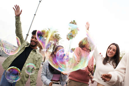 Happy party with soap bubble. Young adult people dancing outdoors. Group of friends having fun