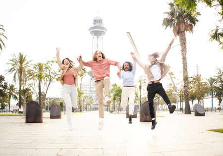 Multiracial friends jumping for joy celebrating successes in the vacation city. People having fun.の写真素材