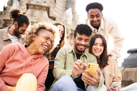 Group of people watching video on the mobile phone. Smiling friends using phone and laughing. Youth culture and technology conceptの写真素材