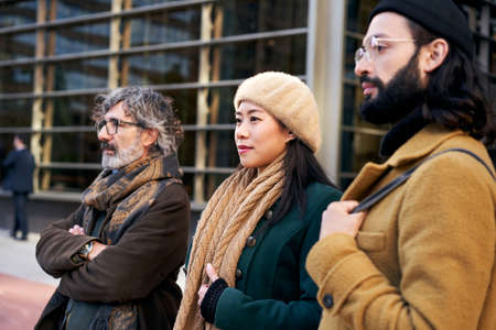 A multi-ethnic group of three people of different ages in a business center posing for a photo.の写真素材