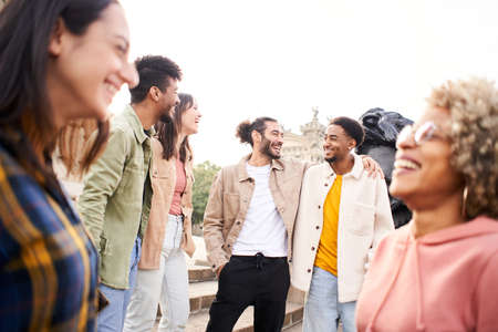 Youth culture. Group of young people laughing and talking outdoors in the city. Happy friends having fun togetherの写真素材