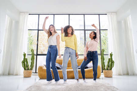 Diverse female friends dancing living room indoors. Multiracial happy women play and celebrate the...