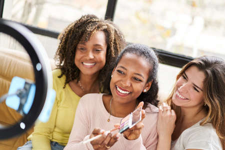 Three Young beautiful women and professional beauty make up artist vlogger or blogger recording...