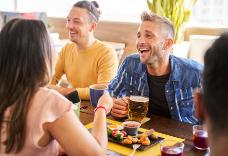 Happy friends having fun together in a bar drinking beer and having appetizer. Youth lifestyle...