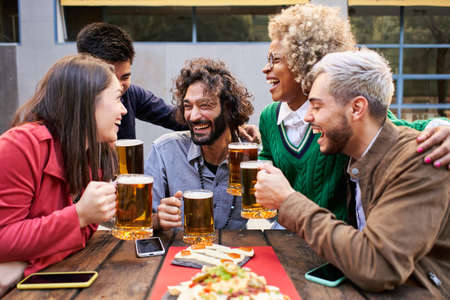 Young friends having fun outdoors. Happy group people enjoying together at Bar terrace. Youth and friendship concept.の写真素材
