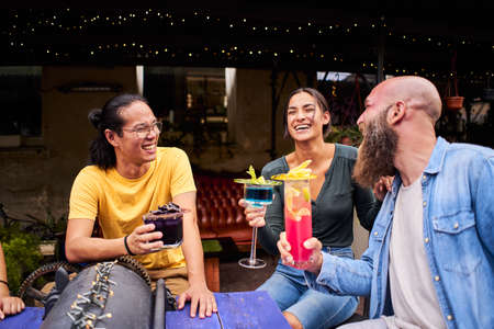Three Friends toasting, saying cheers holding tropical blended fruit margaritas. Watermelon and...