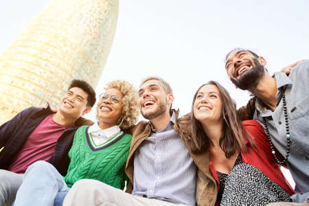 Happy diverse friends having fun hugging together. Multiracial group of young people smiling outdoors hugging together .の写真素材