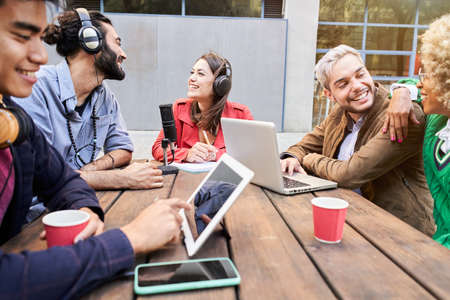 Woman interviewed a man for a podcast outdoors. Young people streaming with casual studio...