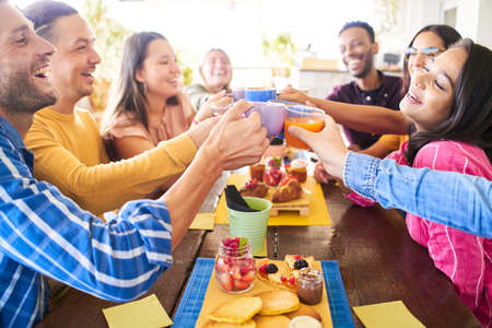 Multicultural People having breakfast drinking coffee and cheers. Happy community fun together in a...