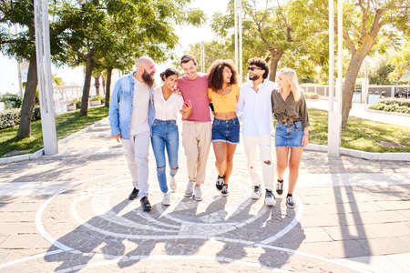 Happy group of smiling friends walk outdoors enjoying the summer holidays and having fun togetherの写真素材