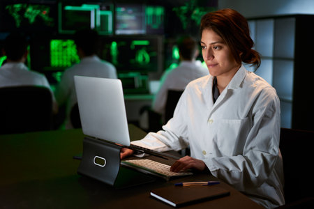 Female Medical Research Scientist using computer laptop. Neurologist Solving Puzzles of the Mind and Brain. In the Laboratory with Multiple Screens Showing Imagesの写真素材