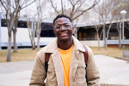 Close up shot of cheerful happy African American teenage boy looking at camera smiling. Intense look of a young student man at campus university high school.の写真素材