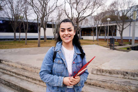 Close up shot of cheerful happy caucasian teenage girl looking at camera smiling. Funny portrait of a young female student with at campus university. Woman laughing at high school.の写真素材