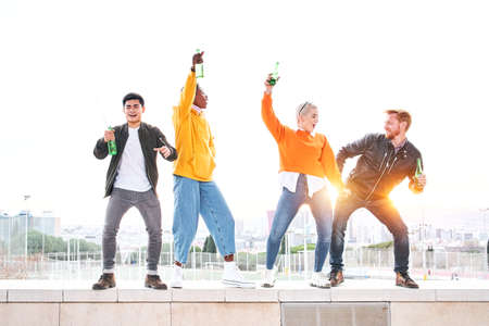 Group of diverse people dancing playfulness outdoors drinking beer and having fun. Happy friends celebrating together the success. Happiness and friendship conceptの写真素材