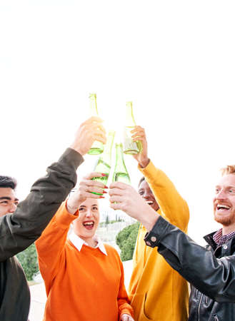 vertical Group of diverse people toasting playfulness outdoors drinking beer and having fun. Happy friends celebrating together the success clinking. Happiness and friendship conceptの写真素材