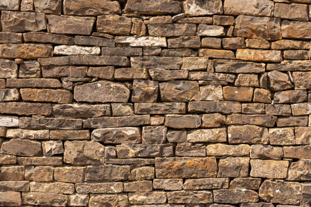 Rustic stone wall texture. Irregular stone wall in natural colors, brown, ocher. Textured background.の写真素材