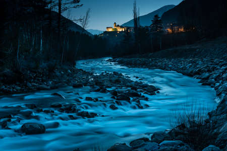 Views of a river at dusk and a lit-up town in the backgroundの写真素材