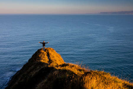 Person with a sense of freedom on a cliff with a panoramic view of the open seaの写真素材