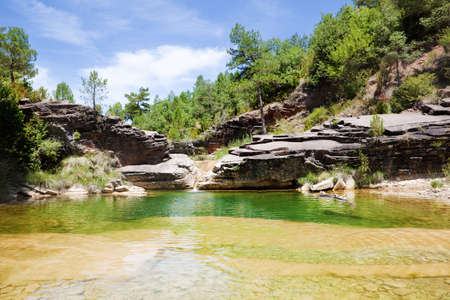 Idyllic small pond of water from a river with mountain sceneryの写真素材