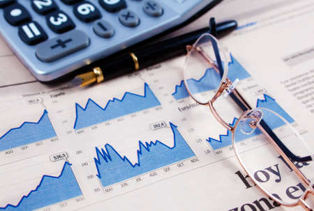 Business background with graphics,glasses,pen and calculatorの写真素材