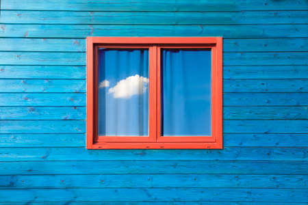 Modern colorful architecture. Wooden blue facade and red window  under blue skyの写真素材