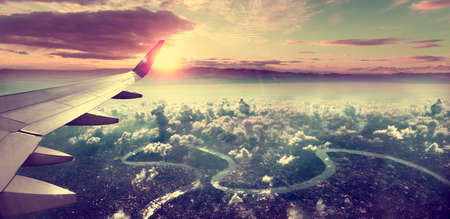 Concept of airplane travel.Flying above the city. Scenery sunset landscape.Sunrise and clouds.Flight...