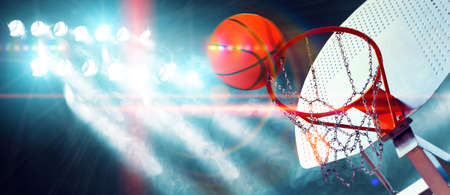 Hoop and ball illuminated by the spotlights. Competition and sport event. Public and crowd...