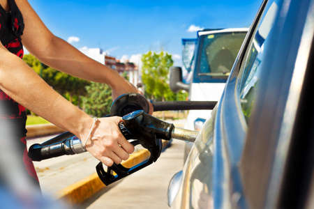 Woman pouring gasoline into the car at the service station.fuel station and car concept