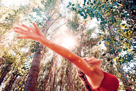 Woman with open arms in nature landscape.Sunlight and treesの写真素材