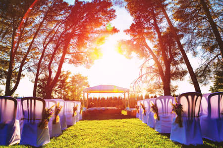 Wedding Ceremony with flowers and trees outside in the garden with sunsetの写真素材