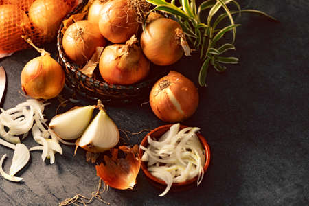 A lot of onions in a basket and plates on a dark and elegant dark textural background.の写真素材