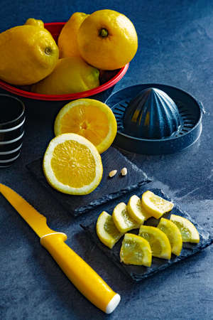 Elegant background design of lemons and lemon slices with squeezer and knife on dark or black cement or stone surface.の写真素材