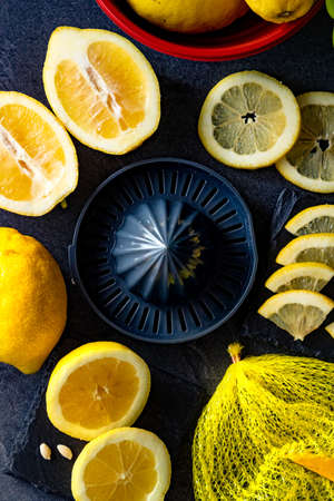 Elegant background design of lemons and lemon slices with squeezer and knife on dark or black cement or stone surface.の写真素材