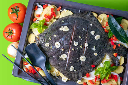 Cooked Whole Turbot fish in baking pan oven with potatoes, bell pepper and aromatic herbs.の写真素材