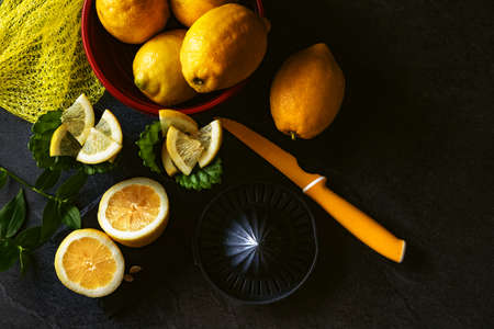 Elegant background design of lemons and lemon slices with squeezer and knife on dark or black cement or stone surface.の写真素材
