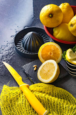 Elegant background design of lemons and lemon slices with squeezer and knife on dark or black cement or stone surface.の写真素材