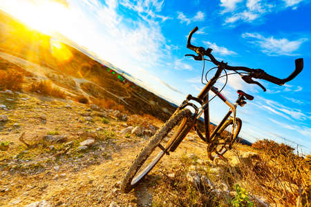 mountain bikes leaned on a rock next to a beautiful down hill trail and sunset landscapeの写真素材