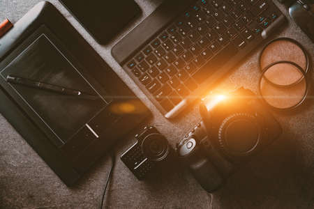 Digital photo workstation over black background. Top view of digital camera, flash, lens and laptop.の写真素材
