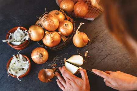 A lot of onions in a basket and plates on a dark and elegant dark textural background.の写真素材