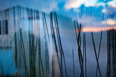 Street view through the wet glass in rainy day. Storm in the city through wet window. Autumn related.の写真素材