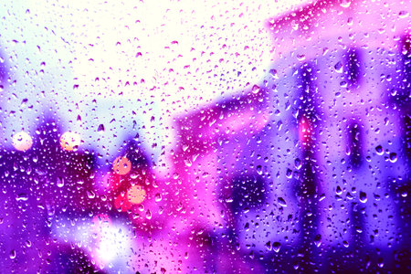 Street view through the wet glass in rainy day. Storm in the city through wet window. Autumn...