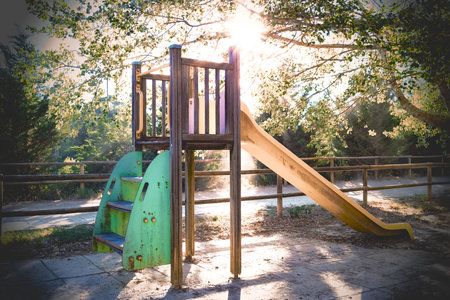 Playground among the trees of the forest, with sunset light and sunbeams between the branches.の写真素材