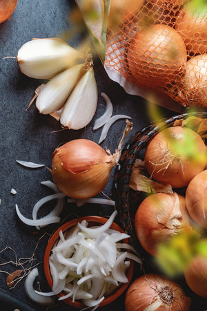 A lot of onions in a basket and plates on a dark and elegant dark textural background.の写真素材