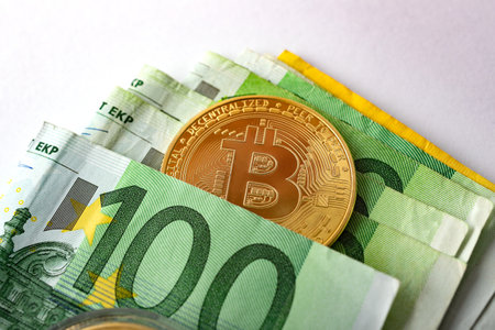 Gold coins with euro bills over white background, close-up image.の写真素材