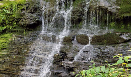 Moss covered waterfall slate rock flowing splashing water