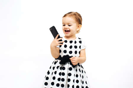 toddler girl laughing at a cell phone she is holding in her handの写真素材