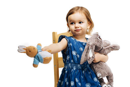 toddler girl sharing and offering a plush toy rabbitの写真素材