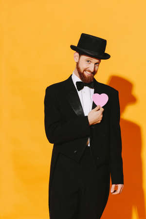 Hopeful smiling man with top hat holding a pink heart, be my valentineの写真素材
